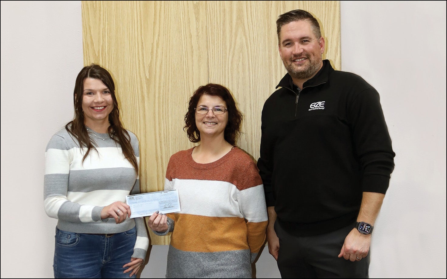 two women and a man holding check