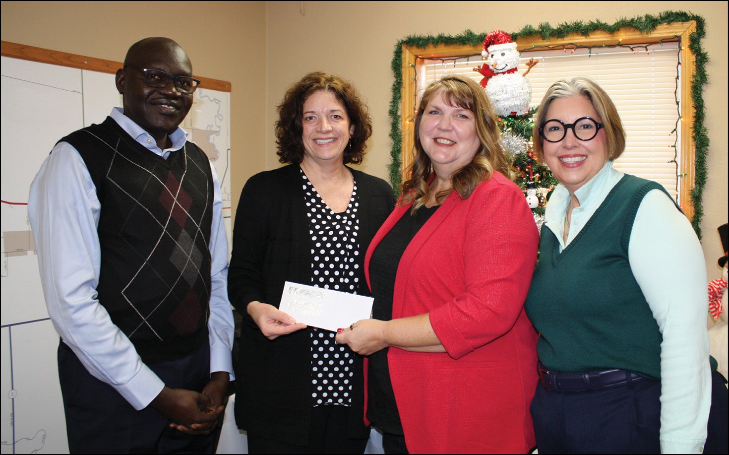 three women and a man holding check